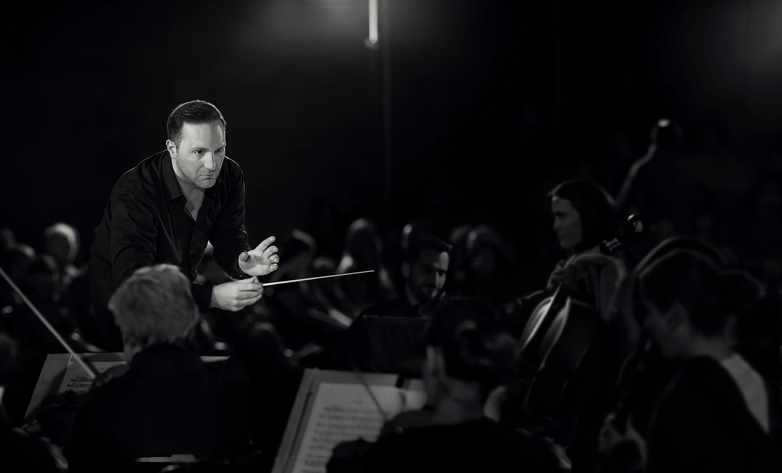 a black and white photo of a conductor in front of an orchestra